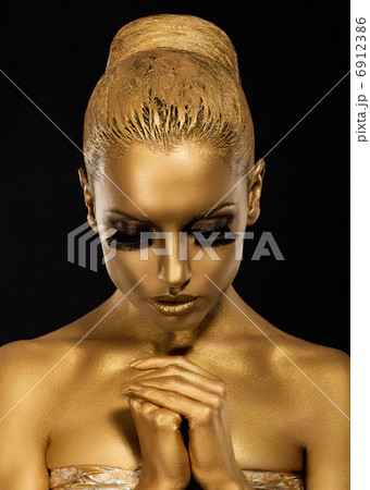 Belief. Styled Woman with praying hands. Golden Makeup 6912386