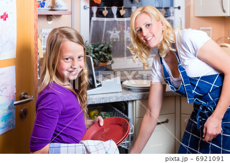 Housewife and daughter doing dishes with dishwasher Housewife and daughter doing dishes with dishwasher 6921091