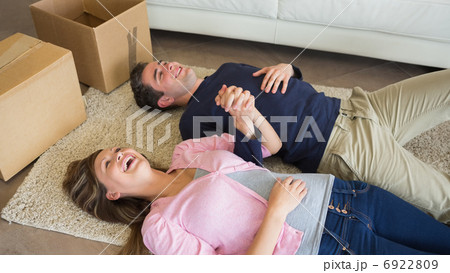 Laughing couple lying on floor with moving boxes Laughing couple lying on floor with moving boxes 6922809