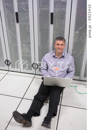 Technician checking the servers on the floor Technician checking the servers on the floor 6923410