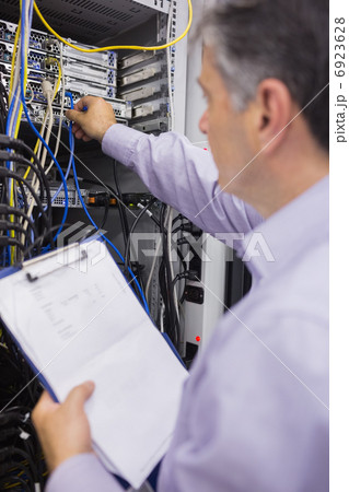 Technician fixing wires of server while holding clipboard 6923628