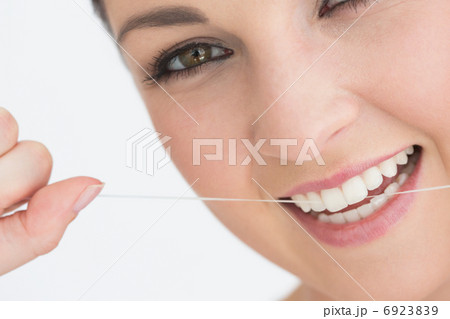 Smiling woman using dental floss 6923839