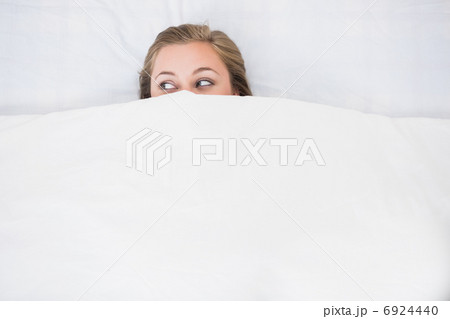 Blonde woman hiding under the duvet 6924440