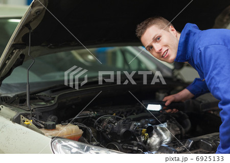 Confident repairman examining car engine 6925133