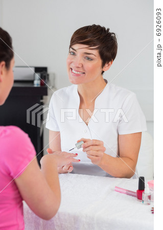 Nail technician applying nail varnish to finger nails Nail technician applying nail varnish to finger nails 6926093