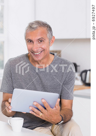 Smiling man using his digital tablet Smiling man using his digital tablet 6927497