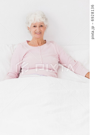 Smiling woman sitting in bed 6928136