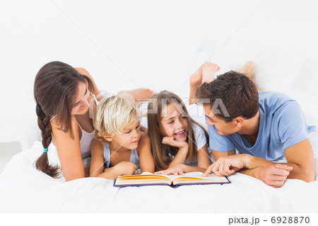 Family reading book on the bed 6928870