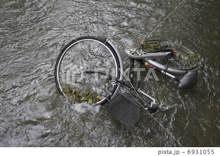 豪雨と強風で川に落ちた自転車の写真素材