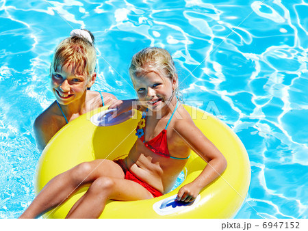 Children sitting on inflatable ring in water. 6947152