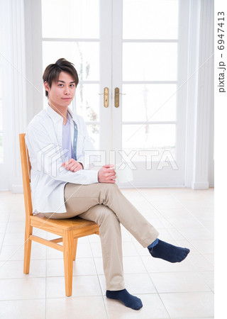 椅子に座ってリラックスしている若い男性 6947413
