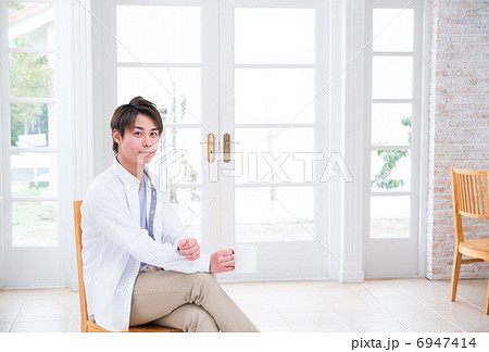 椅子に座ってリラックスしている若い男性 6947414