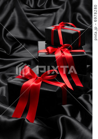 Black gift boxe with red satin ribbons and bows, over black satin Black gift boxe with red satin ribbons and bows, over black satin 6978280