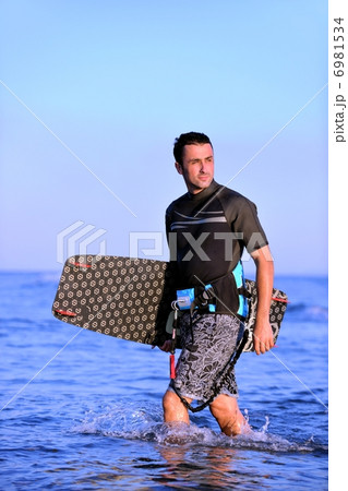 Portrait of a young kitsurf man at beach on sunset 6981534