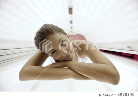 Beautiful young woman tanning in solarium 6988340
