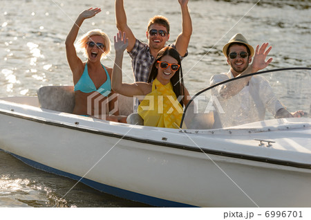 Waving young people sitting in motorboat Waving young people sitting in motorboat 6996701