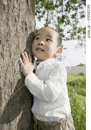 木の幹に耳をあてる男の子 6998296