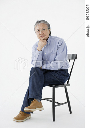椅子に座って頬杖をする中高年の男性の写真素材