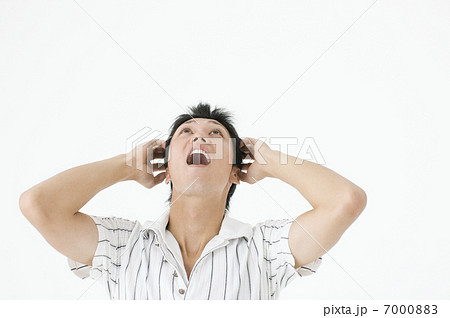 頭を抱えて叫ぶ若者の男性の写真素材