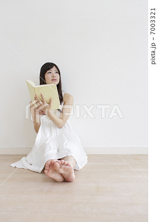 本を持ち床に座る女性の写真素材