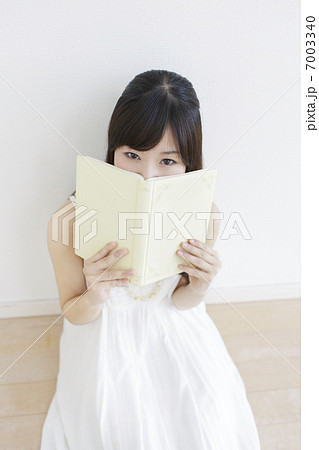本で顔を隠す女性の写真素材