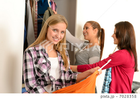 Happy teenagers choosing clothes from wardrobe Happy teenagers choosing clothes from wardrobe 7028358