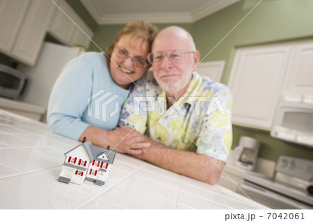 Senior Adult Couple Gazing Over Small Model Home on Counter 7042061