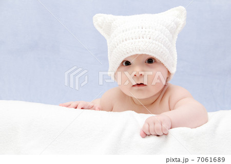 Beautiful baby in white hat lies on bed 7061689