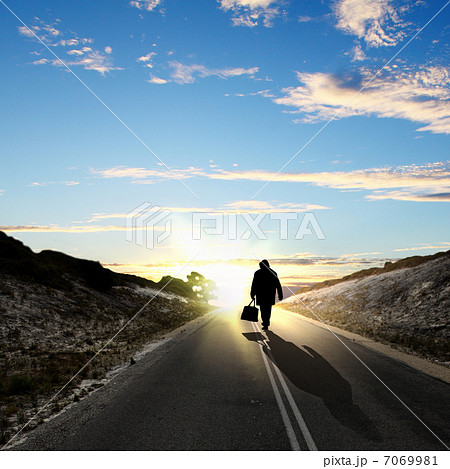 Man walking away at dawn along road Man walking away at dawn along road 7069981