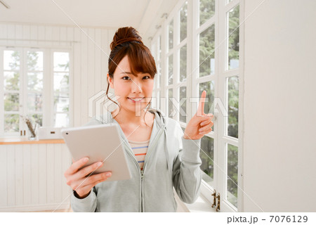 タブレットを指差しで案内する笑顔の女性 7076129