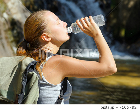 Young woman drinks water by waterfall Young woman drinks water by waterfall 7105785