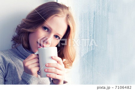 beautiful dreamy young woman with a cup of hot coffee at the win 7106482
