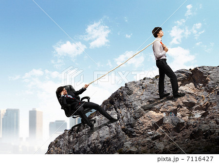 Two businessmen pulling rope atop of mountain 7116427