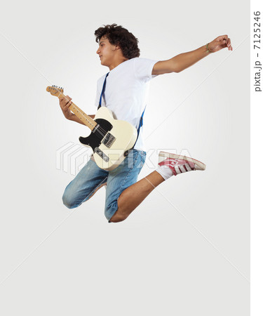 young man playing on electro guitar and jumping young man playing on electro guitar and jumping 7125246