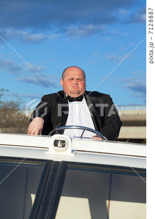 Overweight man in a tuxedo at the helm of a pleasure boat Overweight man in a tuxedo at the helm of a pleasure boat 7128887