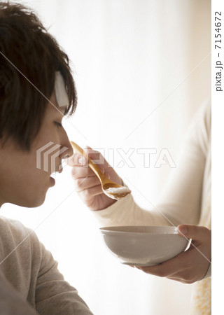 おかゆを食べさせてもらう男性 7154672