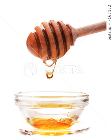 Honey dripping from a wooden honey dipper isolated on white back 7165152