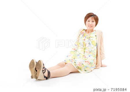 キュートな春夏衣装を着て座る笑顔が素敵な40代女性の写真素材