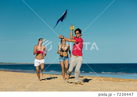 Man and women running on beach with kite Man and women running on beach with kite 7230447
