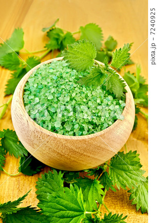 Salt green in a wooden bowl with nettles on the board Salt green in a wooden bowl with nettles on the board 7240925