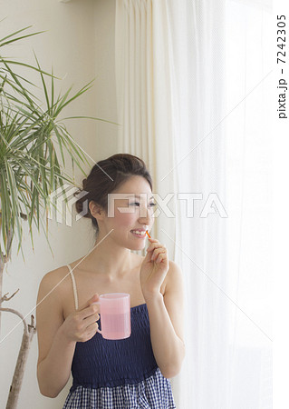 朝 窓辺で歯磨きする女性 7242305