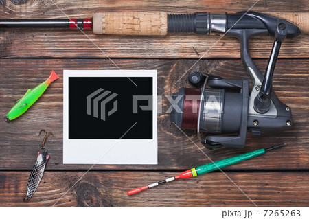 fishing tackle and photo frame on wooden table 7265263