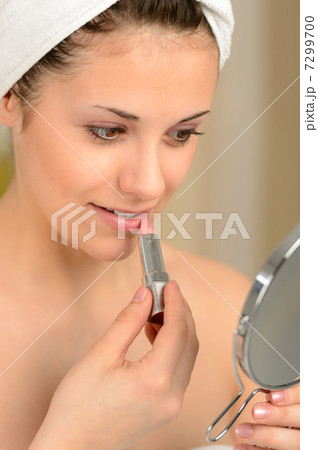 Young teenager girl using lipstick handheld mirror Young teenager girl using lipstick handheld mirror 7299700