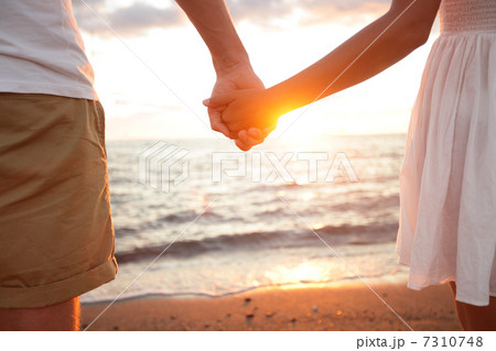 Summer couple holding hands at sunset on beach Summer couple holding hands at sunset on beach 7310748