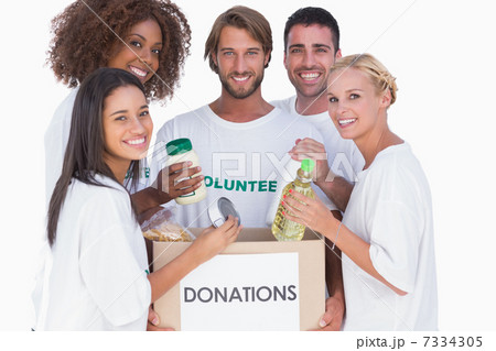 Happy volunteers putting food in donation box 7334305