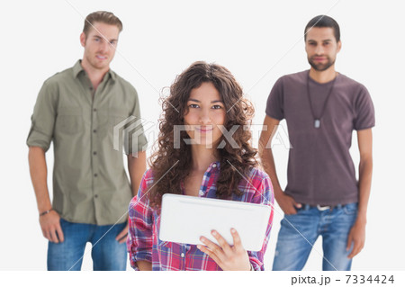 Stylish friends looking at camera with one holding tablet 7334424