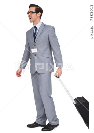 Smiling businessman walking with his suitcase 7335015