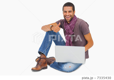 Happy man sitting on floor using laptop giving thumbs up 7335430