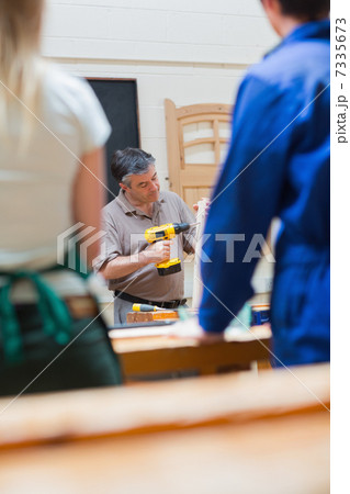 Teacher of a woodworking class explaining 7335673