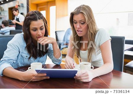 Students watching something shocking on tablet in canteen Students watching something shocking on tablet in canteen 7336134